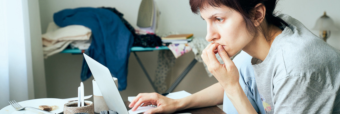 A distraught looking woman stares at a computer screen.