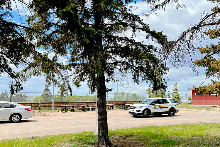 RCMP officers pull over a silver car at a campground.