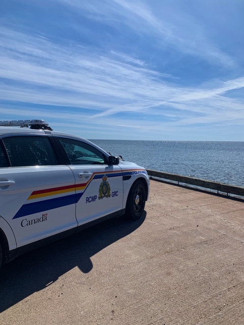 An RCMP police car parked on a concrete pier, overlooking the Northumberland Strait.