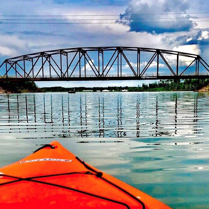 A red kayak on the lake with a bridge in the distance