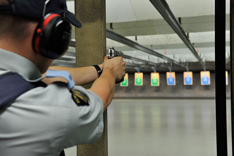 A cadet points a pistol at a paper target