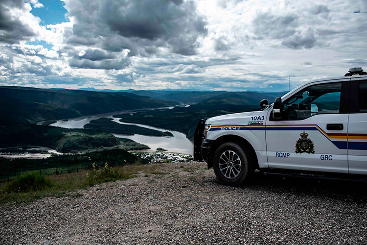 An RCMP truck at the top of a valley, overlooking Dawson City and the Yukon River.