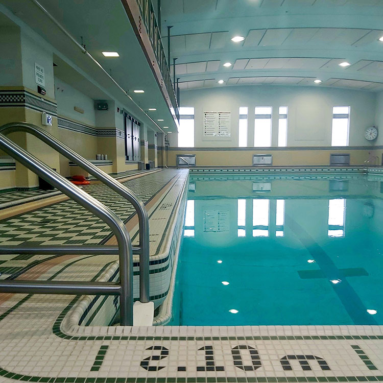 A tiled pool deck looking towards an empty pool.