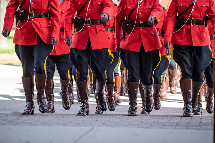 A troop marches outdoors in red serge.