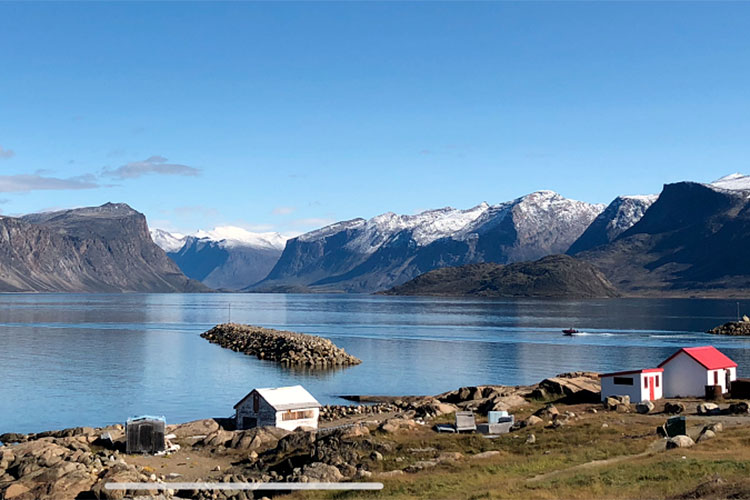 A view of a lake and mountains with snow on top.