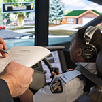 An instructor takes notes as he watches a cadet use the driving simulator.