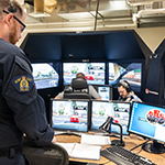 An instructor monitors two cadets as they use the driving simulators. 