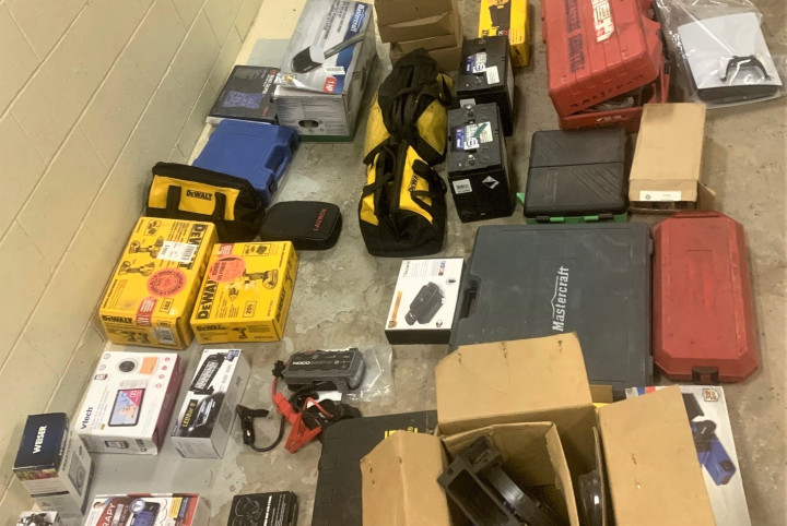 A quantity of stolen merchandise is shown laid on a concrete floor, including tools, boxes, a garage door opener, a baby monitor and a door lock.