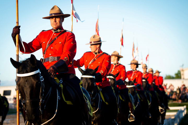 Des gendarmes en tunique rouge sur des chevaux.