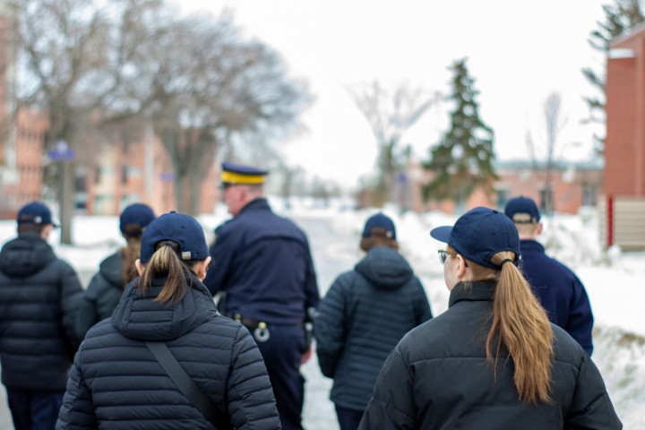 Six personnes marchent avec un policier de la GRC à l'extérieur. 