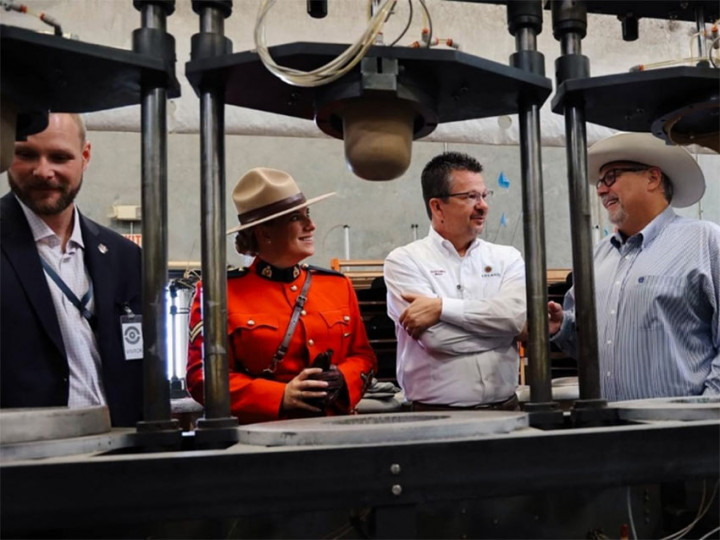 RCMP Matthews McGraw, Cpl. Marie-Michèle Ouimet, Garland Texas Mayor LeMay, and Dorfman Milano Executive stand, chatting, behind a manufacturing line used to make the iconic Stetson hat. 