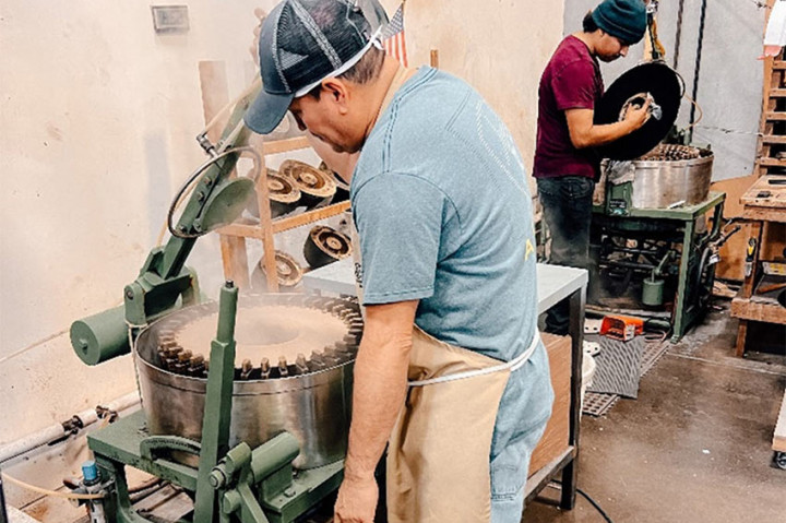 Un employé de l'usine de chapeaux Dorfman Milano se trouve devant une presse à chapeau, où il fabrique un stetson de la GRC.