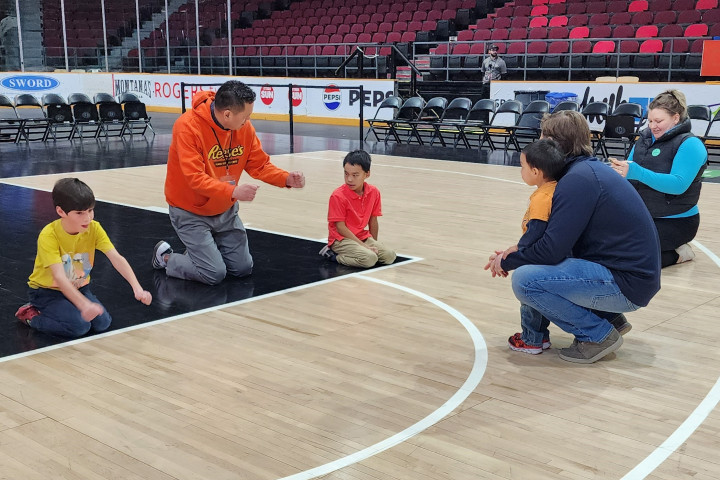 In an arena, Inuit leaders demonstrate and teach a group of youth about the events that take place during Inuit Games.