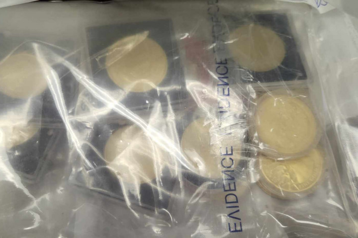 Gold coins inside a clear plastic package are on a table.