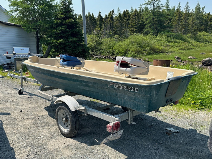 A small green boat on a trailer.