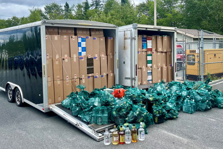 Boxes of tobacco and contraband liquor can be seen inside two utility trailers.