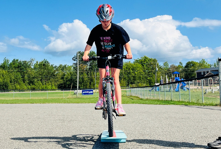 A young person navigates their bicycle across an obstacle