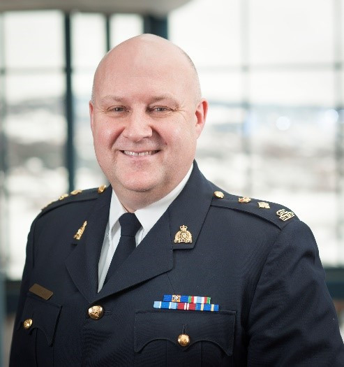 A uniformed police officer is pictured from the chest up and is smiling.