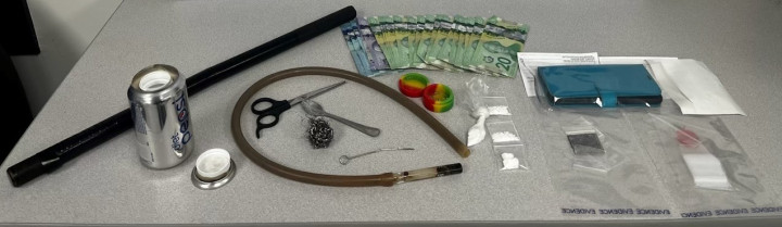 Various items are displayed on a table, including drugs, cash and drug paraphernalia.