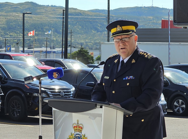 Un agent de la GRC en uniforme bleu se tient à l'extérieur devant un podium. 