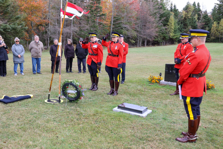 RCMP Officers salute at the headstone of Cst. Joyce Graham