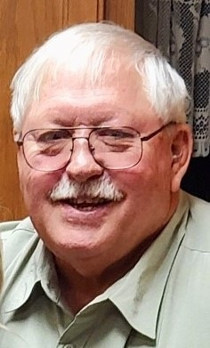 Portrait d'un homme âgé, qui porte des lunettes et a les cheveux blancs.