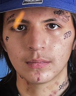 Shayden is described as having brown eyes and short black hair. He has multiple tattoos of words and numbers on his face