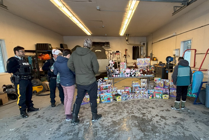 Deux agents de la GRC regardent trois jeunes qui choisissent un jouet parmi tout un tas de jouets.